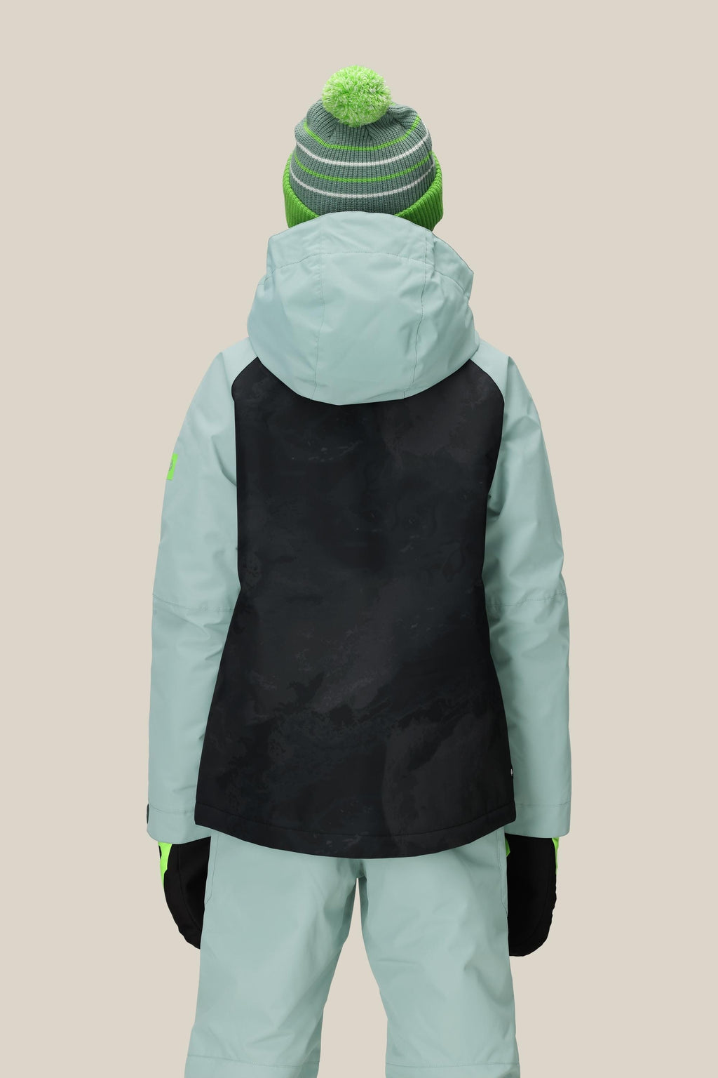 A person is shown from behind wearing the 686 Boys' Hydra™ Insulated Jacket in light blue with a black back panel, paired with matching pants, black gloves, and a green and gray knit hat with a green pom-pom against a plain background.