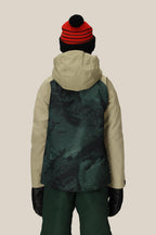 A child wearing the 686 Boys' Hydra™ Insulated Jacket in beige and green, paired with green pants, black gloves, and a red and black striped beanie, stands facing away against a plain beige background.
