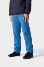 A person showcases the 686 Men's Everywhere® Merino-Lined Pant - Relaxed Fit, paired with a stylish insulated jacket and black sneakers, against a plain light background. The image is cropped below the shoulders to emphasize the pants and shoes.