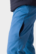A close-up of someone wearing 686 Men's Everywhere® Merino-Lined Pant - Relaxed Fit in bright blue, featuring a zippered side pocket. They’re also sporting a stylish insulated jacket by 686, ideal for chilly days.