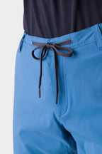 Close-up of a person wearing the 686 Men's Everywhere® Merino-Lined Pant - Relaxed Fit in light blue with a black drawstring, paired with a dark shirt and outerwear—comfort and style by 686 for a perfect casual look.