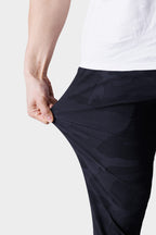 A person wears a white shirt and stretches the fabric of their 686 Men's Everywhere® Featherlight Chino Pant - Slim Fit, highlighting its lightweight flexibility—ideal for a breathable summer wardrobe.