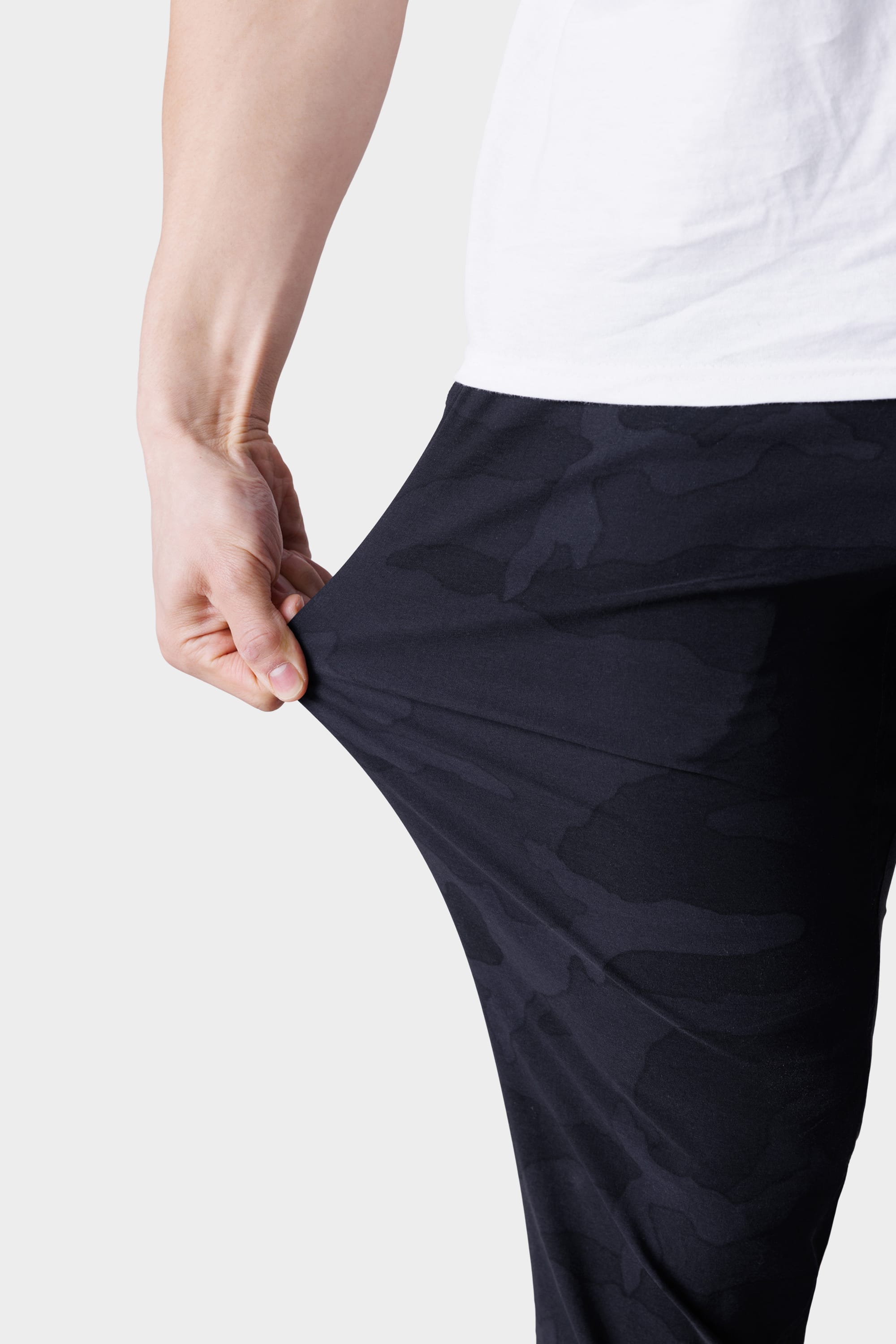 A person wears a white shirt and stretches the fabric of their 686 Men's Everywhere® Featherlight Chino Pant - Slim Fit, highlighting its lightweight flexibility—ideal for a breathable summer wardrobe.