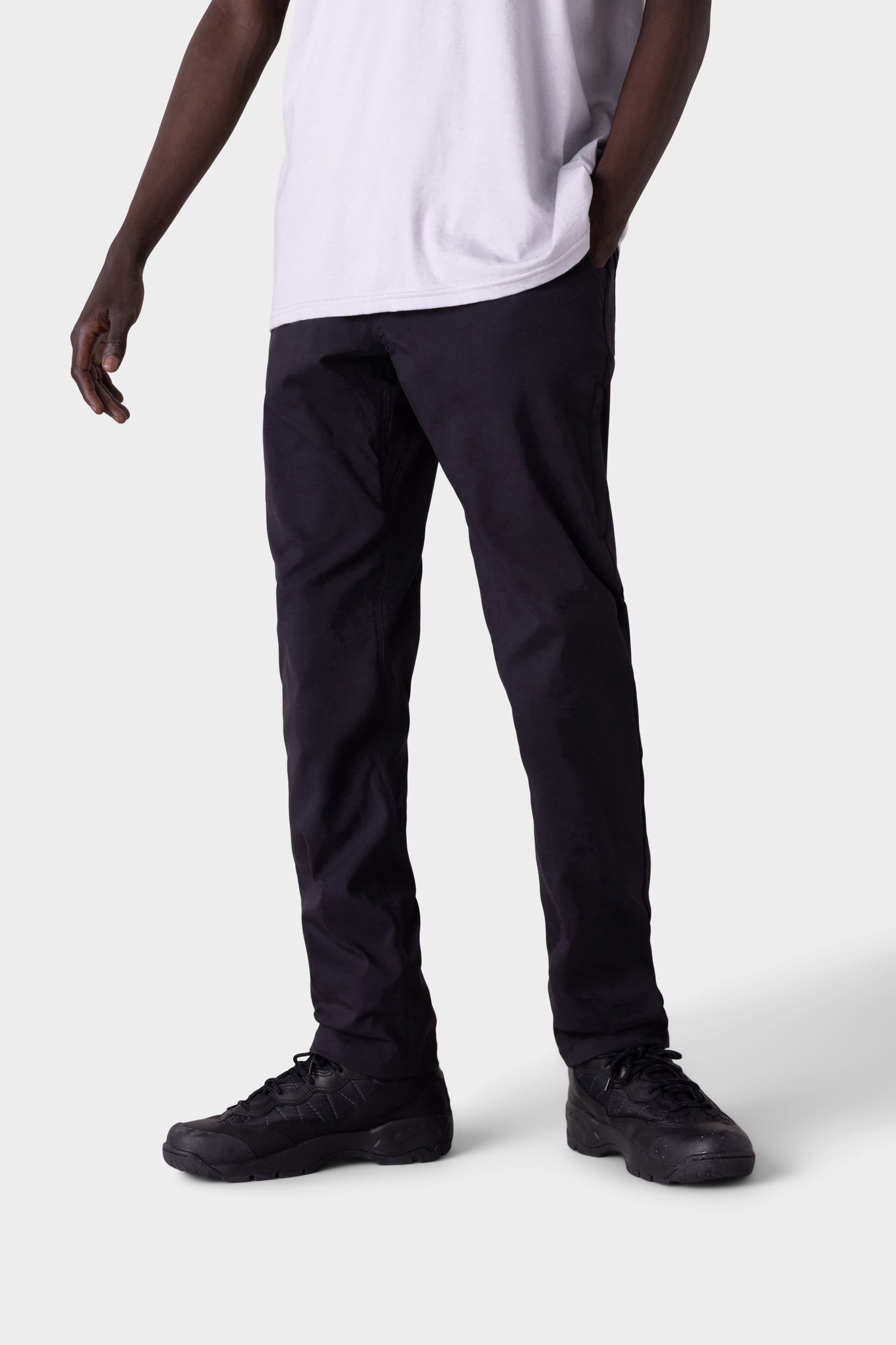 A person stands at an angle against a light gray background, wearing the 686 Men's Everywhere® Merino-Lined Pant - Slim Fit with one hand in a pocket—ideal for warmer or dry conditions.