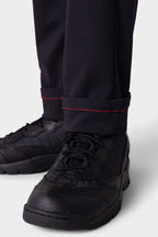 Close-up of a person wearing 686 Men's Everywhere® Merino-Lined Pant - Slim Fit in black, featuring red stitching near the cuffs—ideal for staying warm and dry in cold conditions.