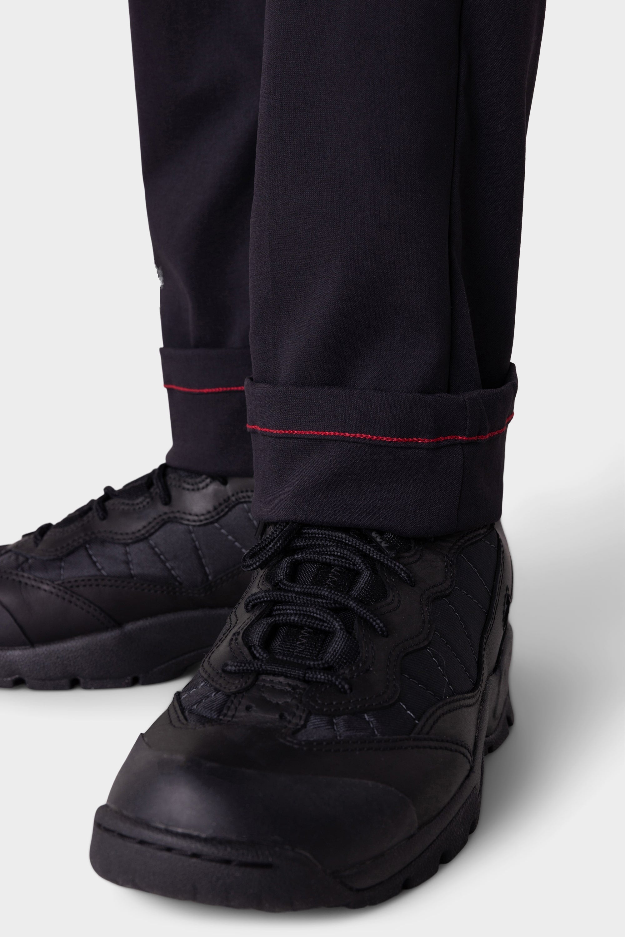 Close-up of a person wearing 686 Men's Everywhere® Merino-Lined Pant - Slim Fit in black, featuring red stitching near the cuffs—ideal for staying warm and dry in cold conditions.