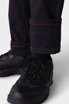 Close-up of a person wearing 686 Men's Everywhere® Merino-Lined Pant - Slim Fit with red-stitched, rolled cuffs, dark socks, and black lace-up sneakers—ideal from 686 for warmth and dryness in colder conditions.