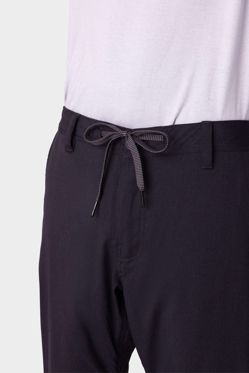 A person wears 686 Men's Everywhere® Merino-Lined Pant - Slim Fit in dark color, featuring a visible drawstring at the waist; ideal for warmth in cold conditions, shown from mid-torso to upper thigh.
