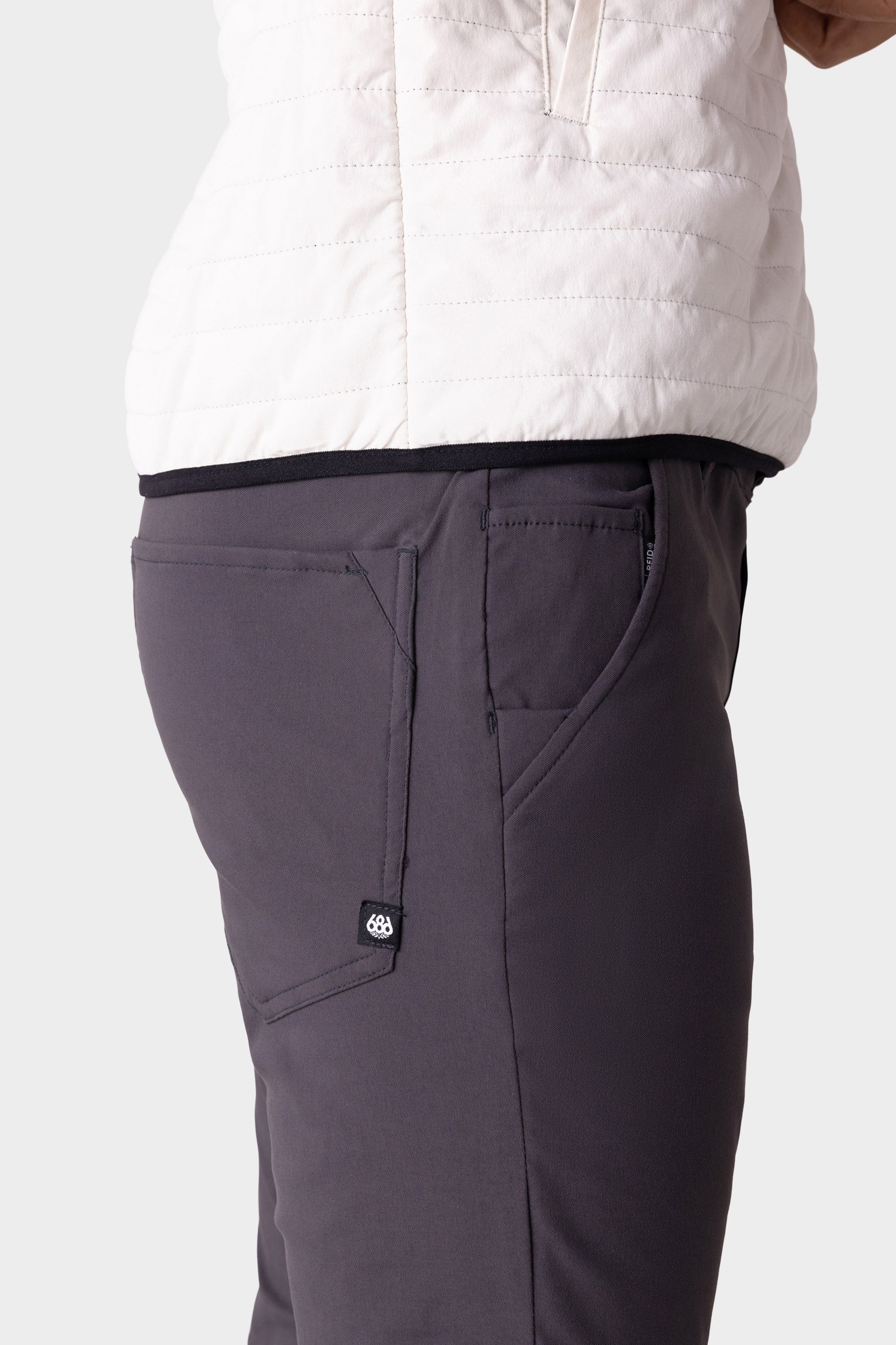 A person wearing the 686 Men's Everywhere® Merino-Lined Pant - Slim Fit in gray, featuring visible side pockets, shown waist to mid-thigh against a plain background—an ideal choice for colder conditions.