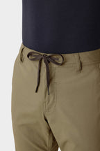 Close-up of a person wearing 686 Men's Everywhere® Merino-Lined Pant - Slim Fit in light brown, featuring a black drawstring belt. Paired with a tucked-in dark shirt, these pants from 686 are perfect for warmth in colder conditions.