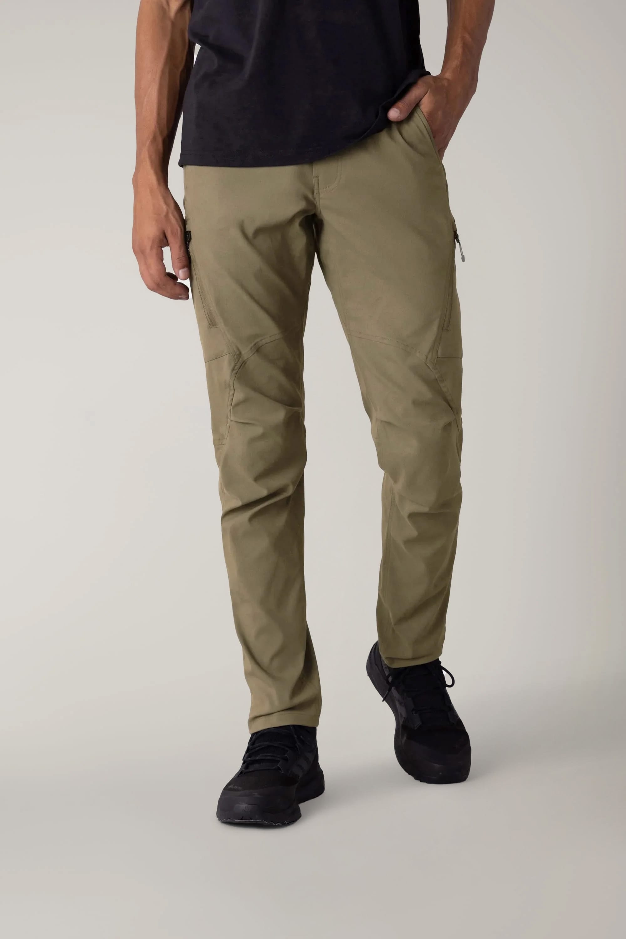 A person wearing 686 Men's Anything Cargo Pant - Slim Fit in olive green with black shoes stands against a plain light background, showing only the lower half of their body, ready for any adventure.