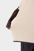 A person demonstrates the stretchiness of the 686 Men's Let's Go Tech Tee by pulling the lightweight fabric outward; only their arm, hand, and part of their body in the dark-trimmed 686 shirt are visible against a plain background.