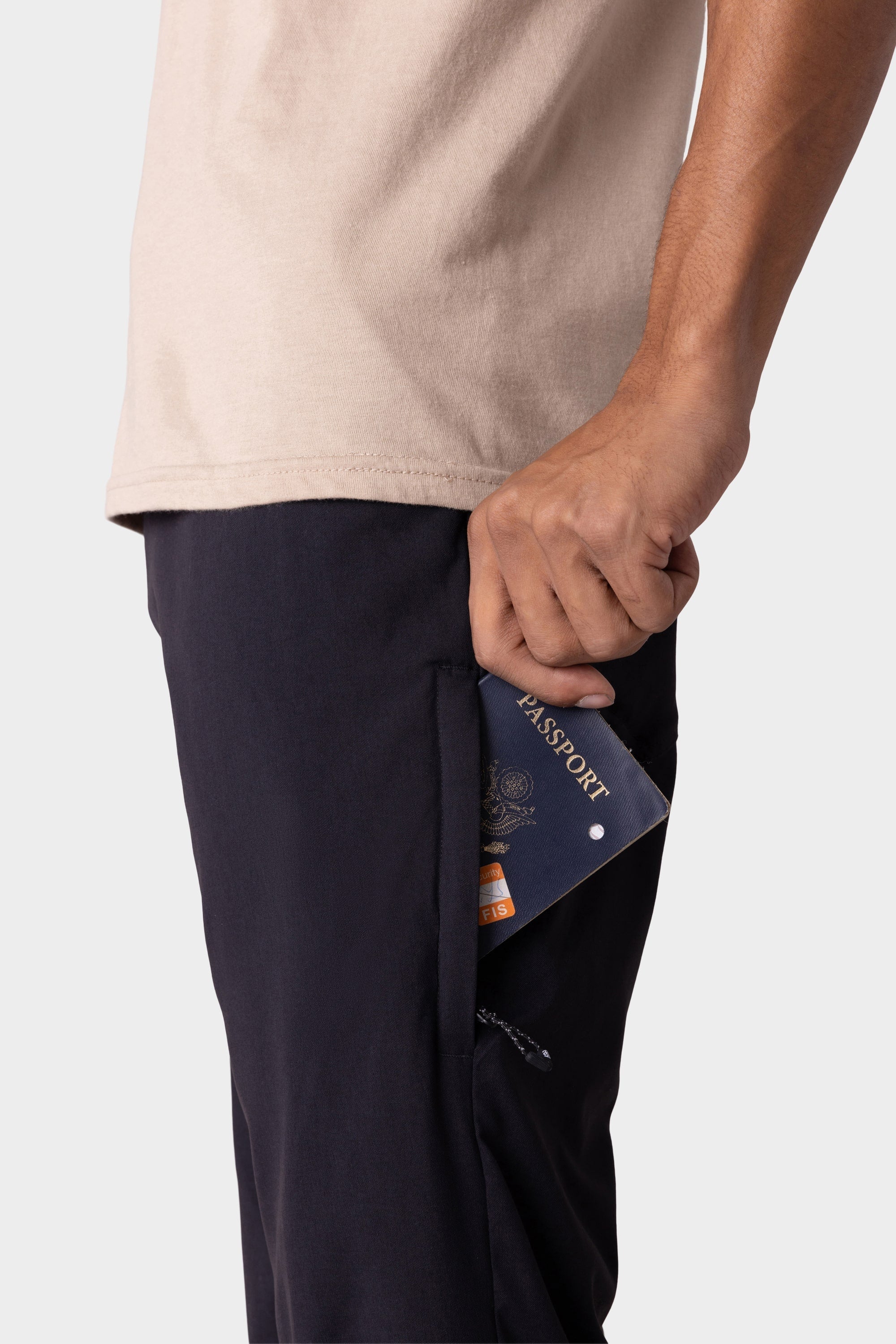 Wearing the 686 Men's Everywhere® Merino-Lined Pant - Relaxed Fit, a traveler slips a passport and boarding pass into the side pocket of their pants.