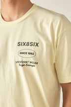A person wears the 686 Unwork Wear Authentic S/S Tee, a pale yellow 100% cotton mens shirt with SIX8SIX, SINCE 1992, UNWORK® WEAR, Tough Enough in black on the left chest. Photo shows upper torso and part of neck. Brand: 686.