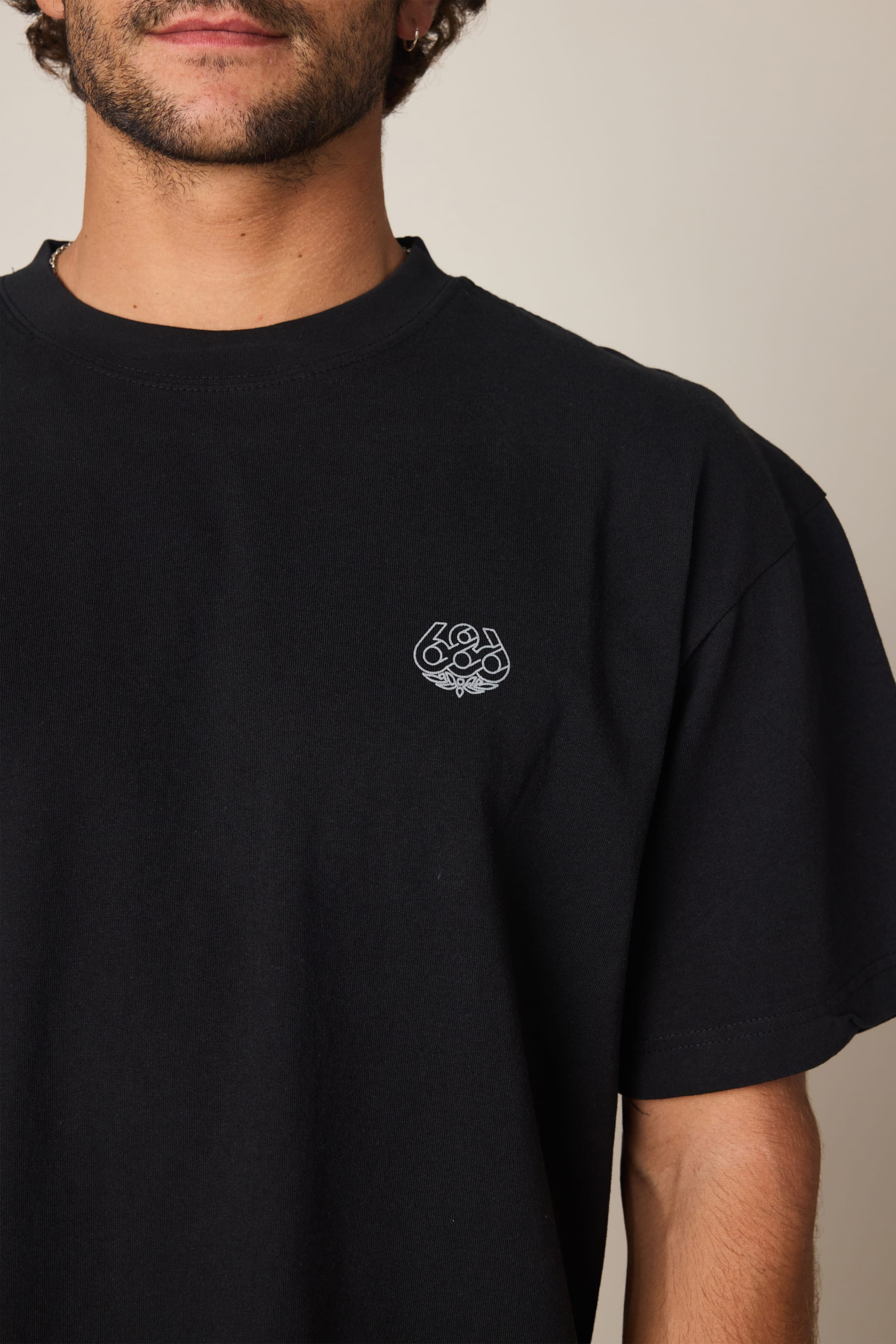 A person wearing the 686 Engineered Relaxed SS Tee by 686, a plain black men's t-shirt with a small white graphic logo on the left chest. Only the upper torso and part of the face are visible against a neutral background.