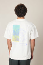 A person with curly hair faces away, wearing the 686 Peaks Relaxed SS Tee by 686—a 100% cotton men’s T-shirt with a colorful mountain and abstract line art graphic on the back in blue, green, and purple tones.