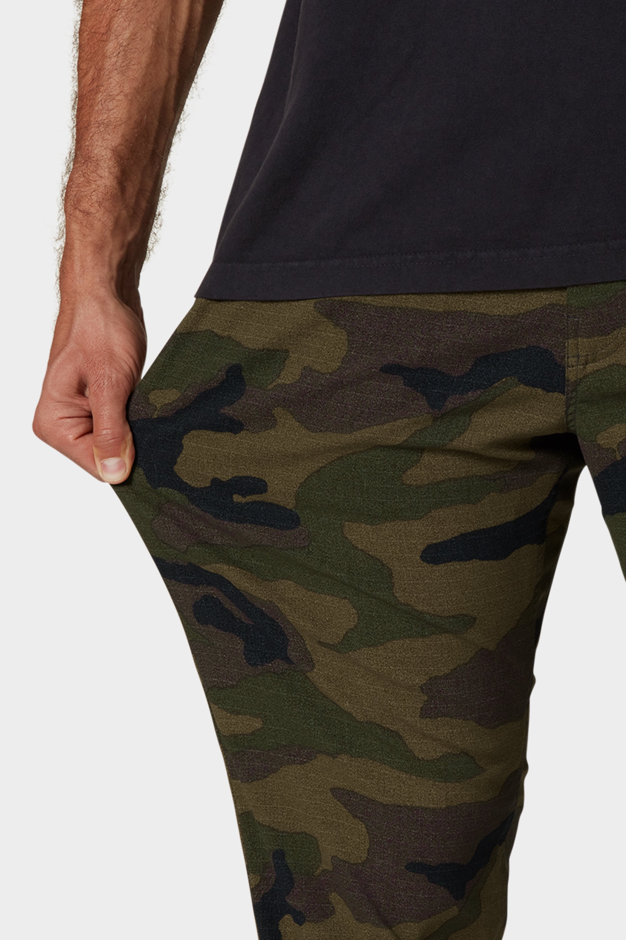 A person wearing 686 Men's Everywhere® Merino-Lined Pants in Relaxed Fit stretches the fabric to show off their comfort and flexibility, making them ideal for pairing with stylish outerwear.