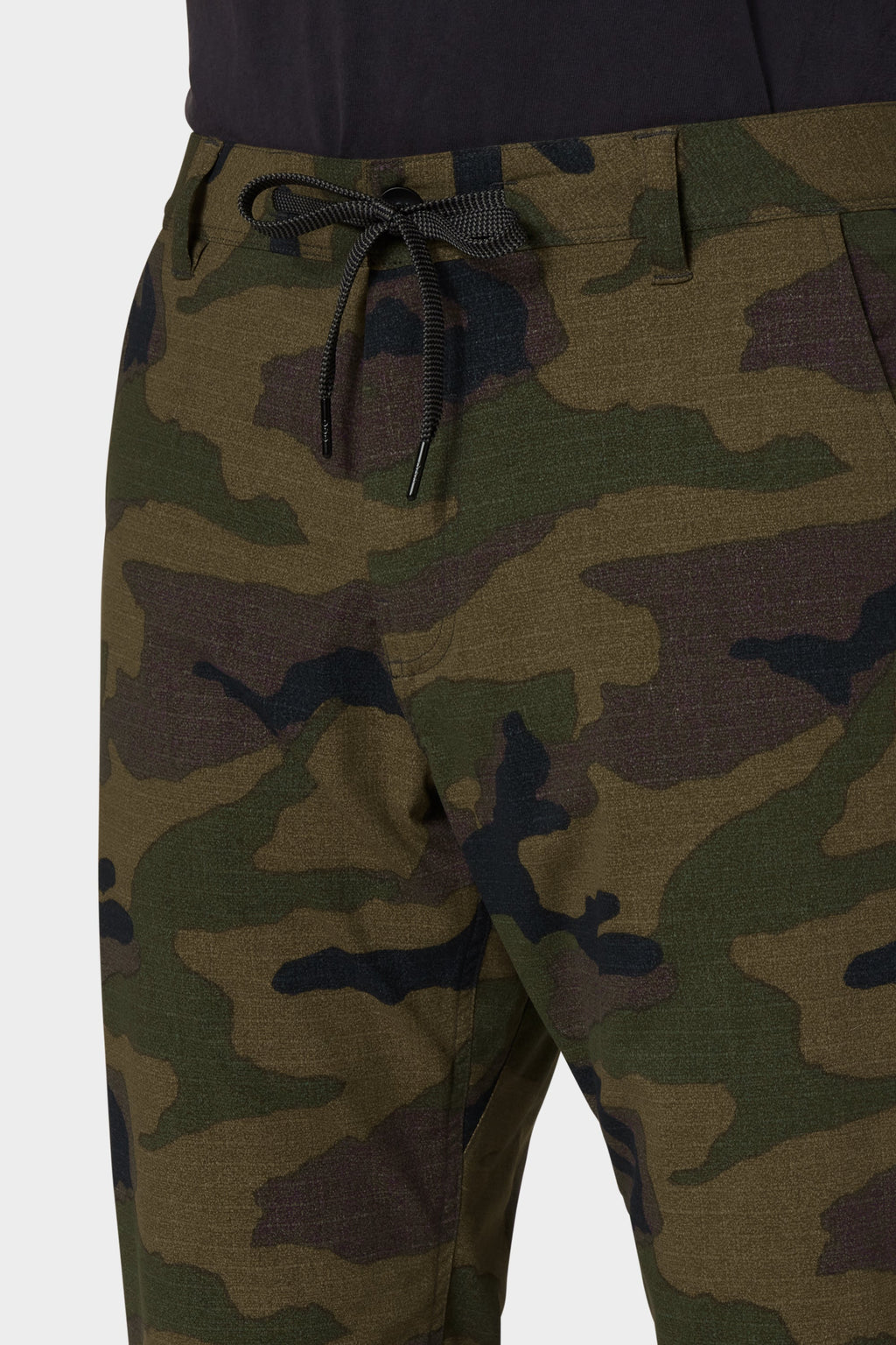 Close-up of a person wearing 686 Men's Everywhere® Merino-Lined Pant - Relaxed Fit in camo, paired with a dark shirt and insulated jacket. Only the waist and upper legs are visible. Brand: 686.