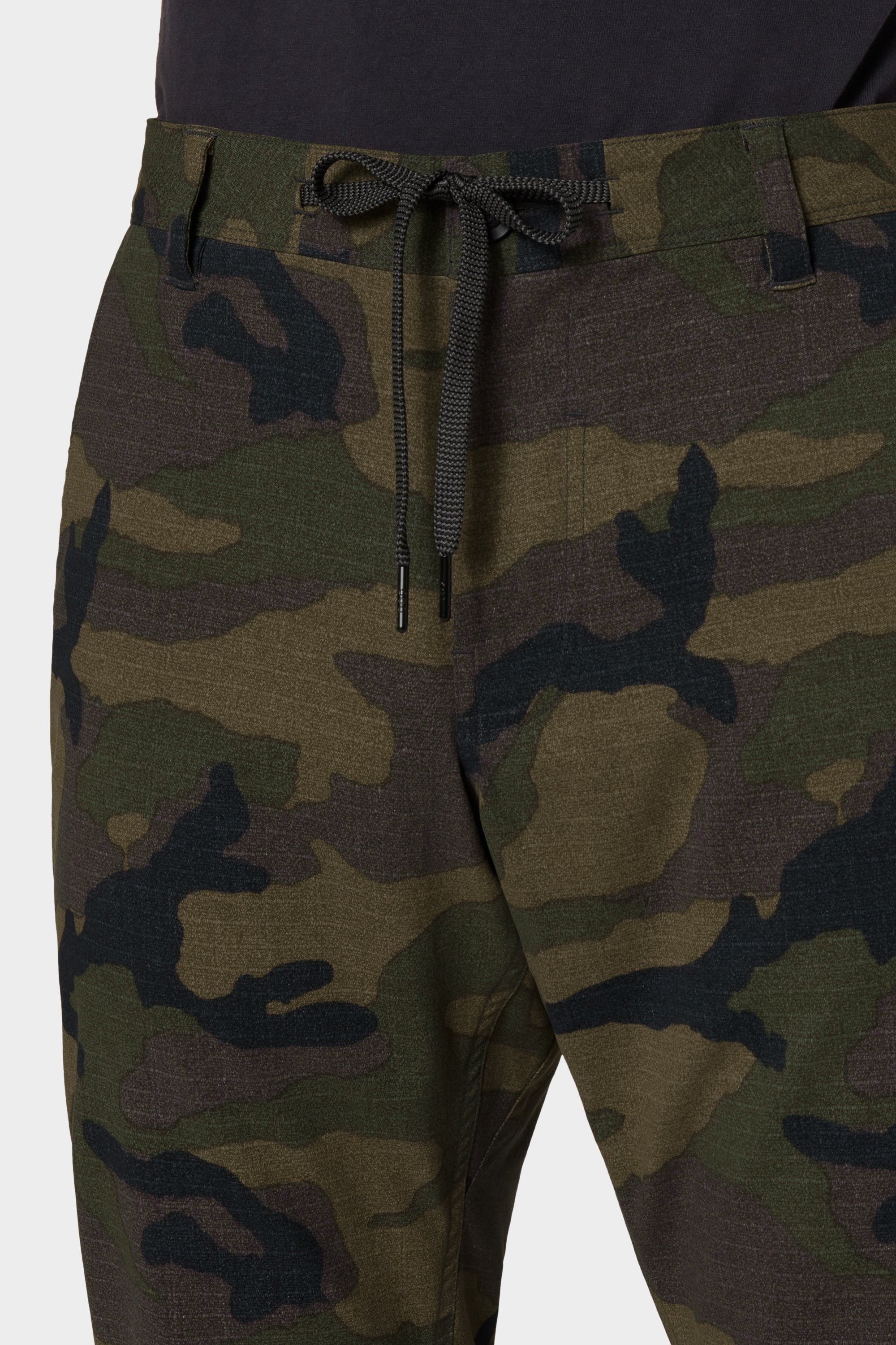 Close-up of a person wearing 686 Men's Everywhere® Merino-Lined Pant - Slim Fit in a camouflage pattern with a black drawstring, paired with a dark shirt—ideal from 686 for staying cozy in colder weather.