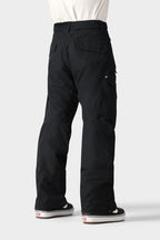 A person is shown from the waist down, standing with their back to the camera against a light gray background, wearing 686 Men's SMARTY® 3-in-1 Cargo Pant and black-and-white sneakers.
