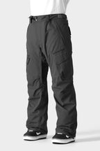 A person wears the 686 Men's SMARTY® 3-in-1 Cargo Pant by 686, featuring a removable liner and zipper details, paired with black-and-white sneakers against a light gray background.