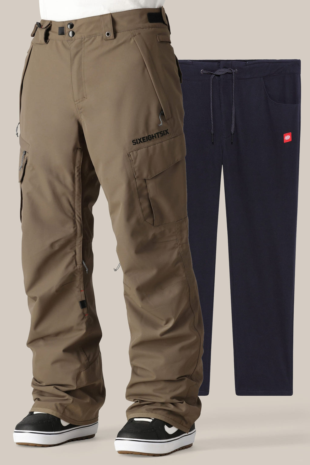 A person in brown 686 Men's SMARTY® 3-in-1 Cargo Pant and black-and-white sneakers stands before navy blue drawstring sweatpants with a removable liner, offering three ways to wear, displayed on a plain background.