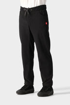 A person wears the 686 Men's SMARTY® 3-in-1 Cargo Pant with side pockets and a small red logo, paired with black sneakers and a white shirt. The pants feature a drawstring waist and three wear options. Background is plain light gray. Brand: 686.