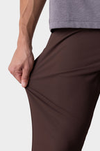 A person in a grey shirt and 686 Men's Everywhere® Pant - Slim Fit stretches the fabric to show its flexibility.