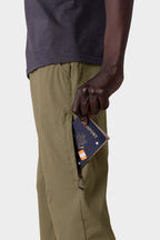 Someone holds a passport in their pocket while wearing the 686 Everywhere® Pant - Slim Fit by 686.