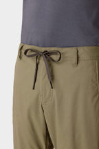 Close-up of a person wearing 686 Men's Everywhere® Pant - Slim Fit in light olive green, featuring a black-and-white drawstring waistband, paired with a dark gray shirt. Focus is on the waistband and drawstring.