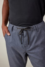 A person wearing a black shirt and 686 Men’s Everywhere® Pant - Slim Fit in light blue, with their left hand in their pocket, shown from waist to mid-thigh.