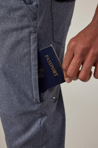 A hand places a navy blue passport into the front pocket of 686 Men's Everywhere® Pant - Slim Fit by 686.