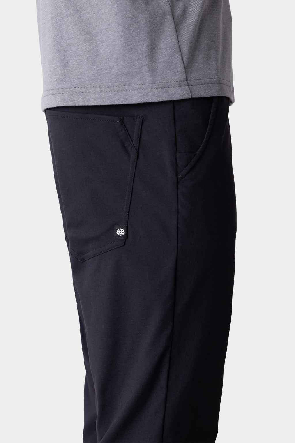 A person wearing 686 Men's Everywhere® Pant - Slim Fit in dark navy, featuring a visible side pocket and button, shown waist down against a plain background.