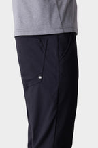 A person wearing 686 Men's Everywhere® Pant - Slim Fit in dark navy, featuring a visible side pocket and button, shown waist down against a plain background.