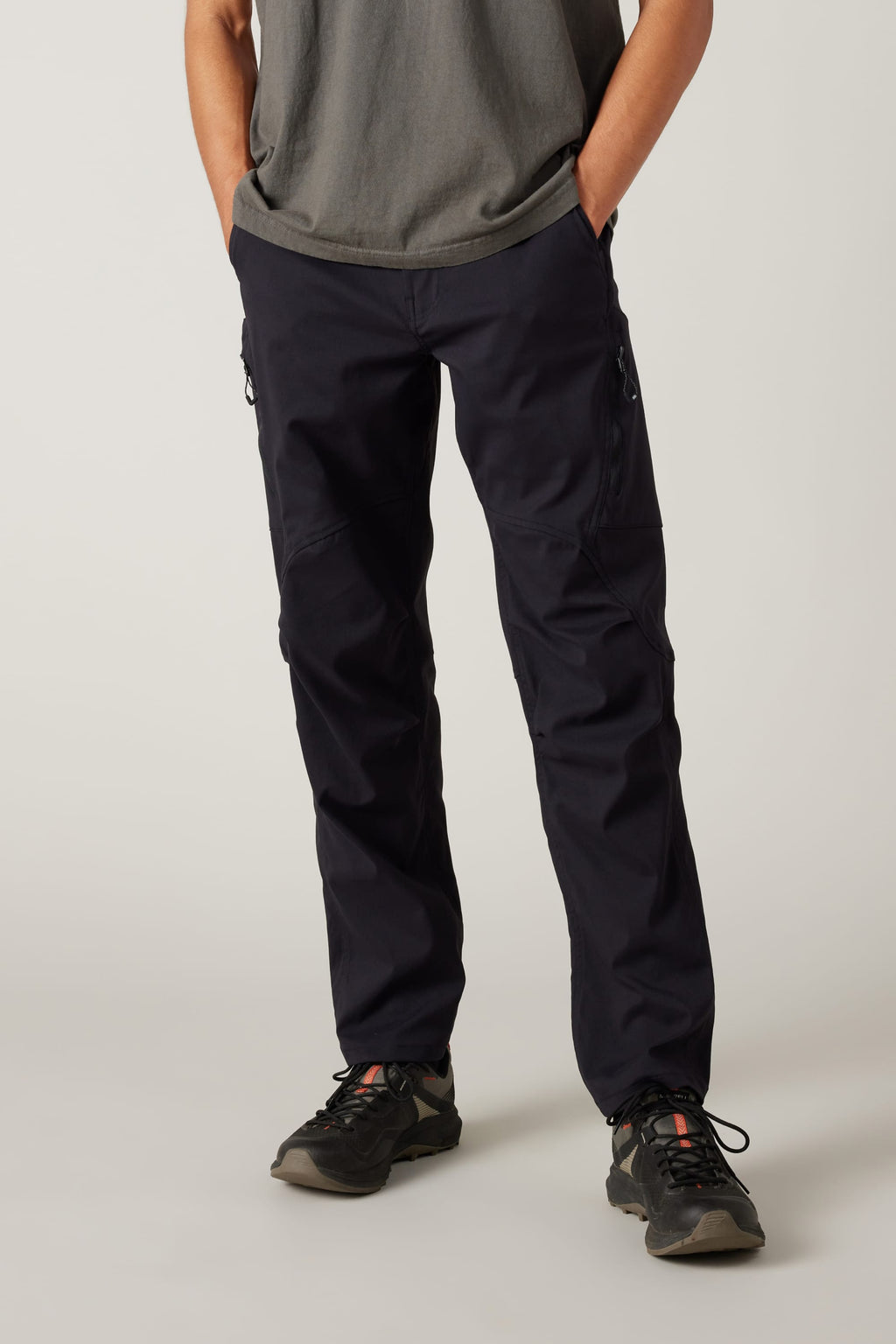 A person wearing a grey t-shirt, 686 Men's Anything Cargo Pant - Relaxed Fit by 686, and black hiking shoes stands with hands in pockets, facing forward against a plain light background.