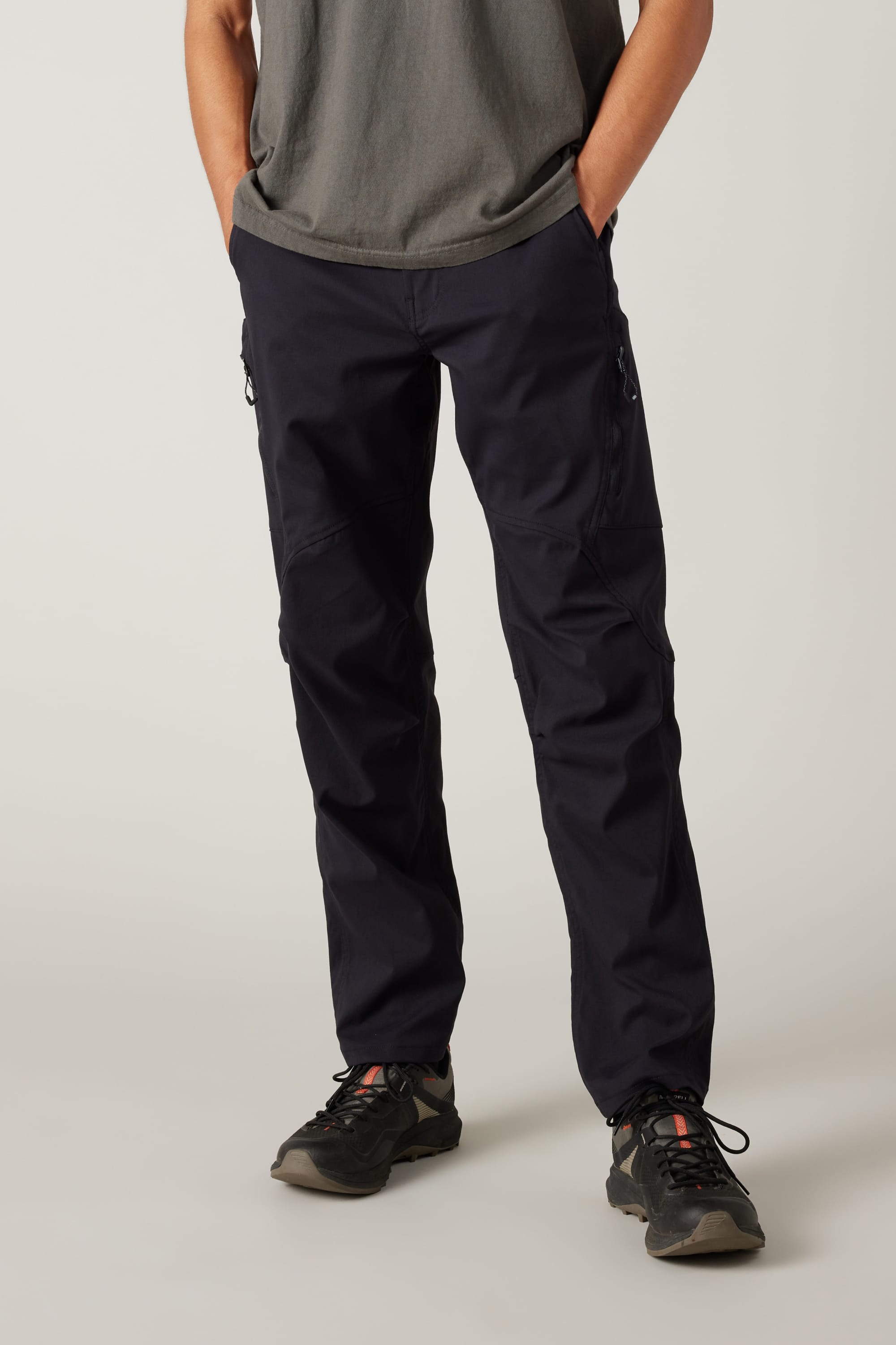 A person wearing a grey t-shirt, 686 Men's Anything Cargo Pant - Relaxed Fit by 686, and black hiking shoes stands with hands in pockets, facing forward against a plain light background.