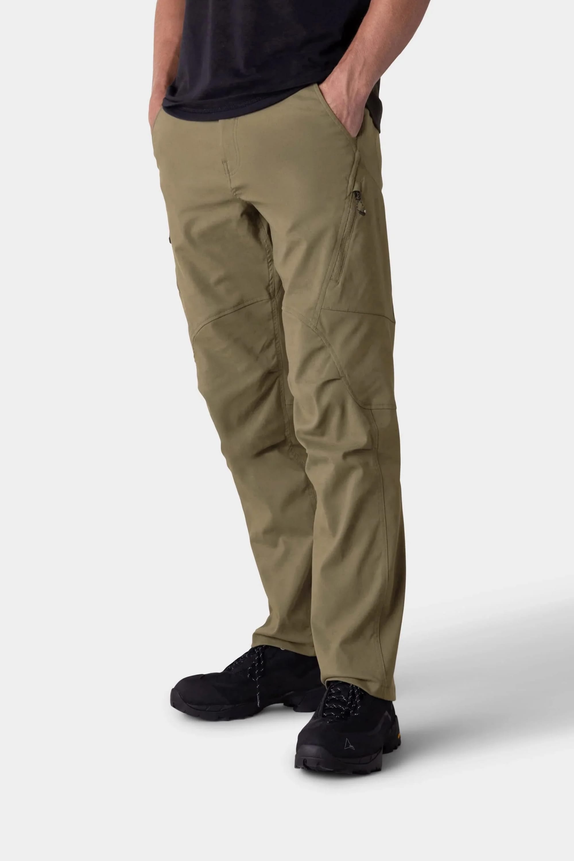 A person models the 686 Men's Anything Cargo Pant - Relaxed Fit, featuring 13 pockets, paired with black shoes. The shot shows only the lower body, hands in pockets, against a plain light background.