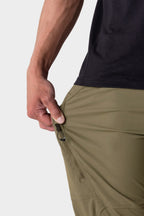 A person in 686 Men's Anything Cargo Pant - Relaxed Fit demonstrates the innovative 13-pocket design by unzipping a side pocket.
