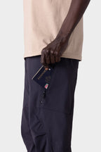 A person in 686 Men's Anything Cargo Pant - Relaxed Fit slips a passport into a zippered side pocket, showcasing the 13-pocket design by 686 and blending function with style.