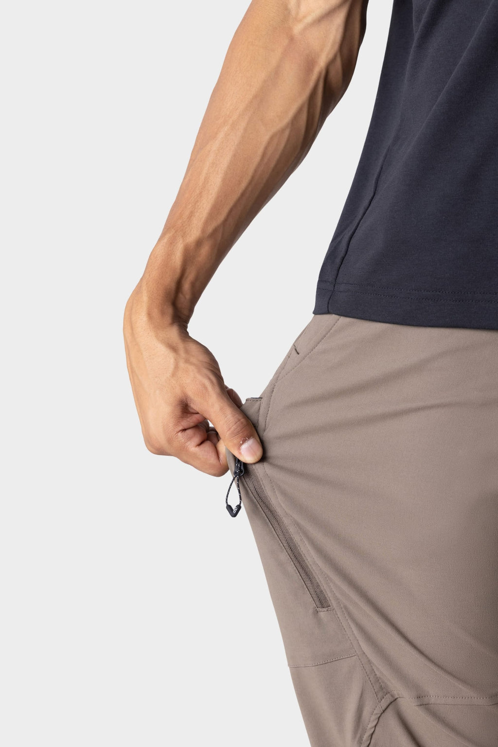 A man in the 686 Men's Anything Cargo Pant - Relaxed Fit by 686 pulls a side pocket zipper, showcasing the pant’s versatile 4-way stretch and flexible design.