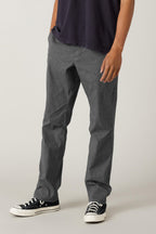 A person wearing a dark short-sleeve shirt, 686 Men's Everywhere® Pant - Relaxed Fit by 686, and black-and-white sneakers stands against a plain light background, with their left hand resting near their pocket.