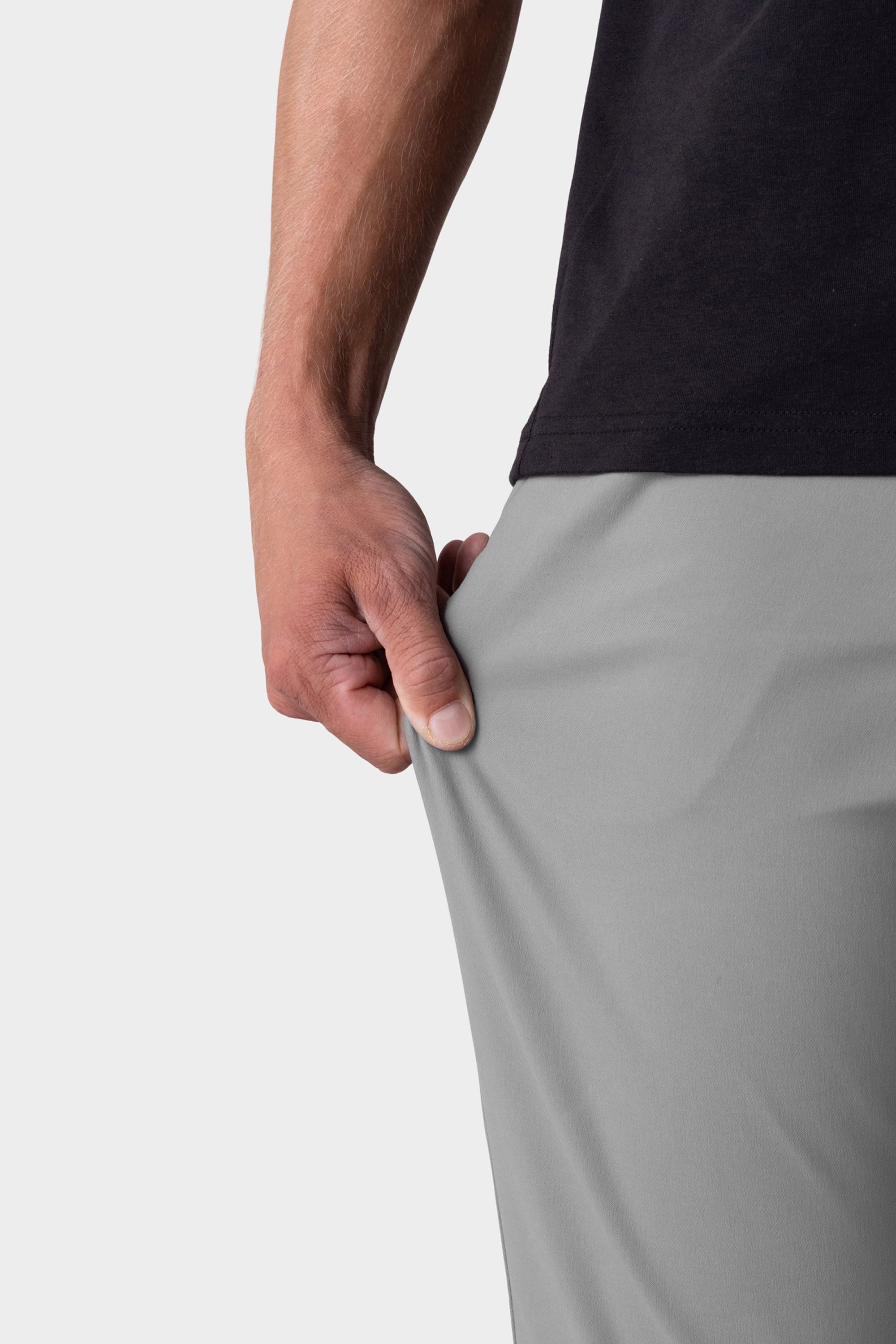 A person wearing a black shirt and 686 Men's Everywhere® Pant - Relaxed Fit in light gray stretches the fabric with their right hand, showcasing the flexibility of these 686 pants.