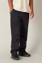 A person stands against a plain background, showing only the lower half while wearing 686 Men's Everywhere® Pant - Relaxed Fit by 686, with one hand in a pocket.