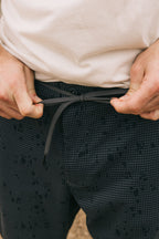 Close-up of hands adjusting the drawstring waistband on 686 Men's Everywhere® Pant - Relaxed Fit. The person wears a light shirt with only their hands and torso visible, highlighting the breathable design from 686.