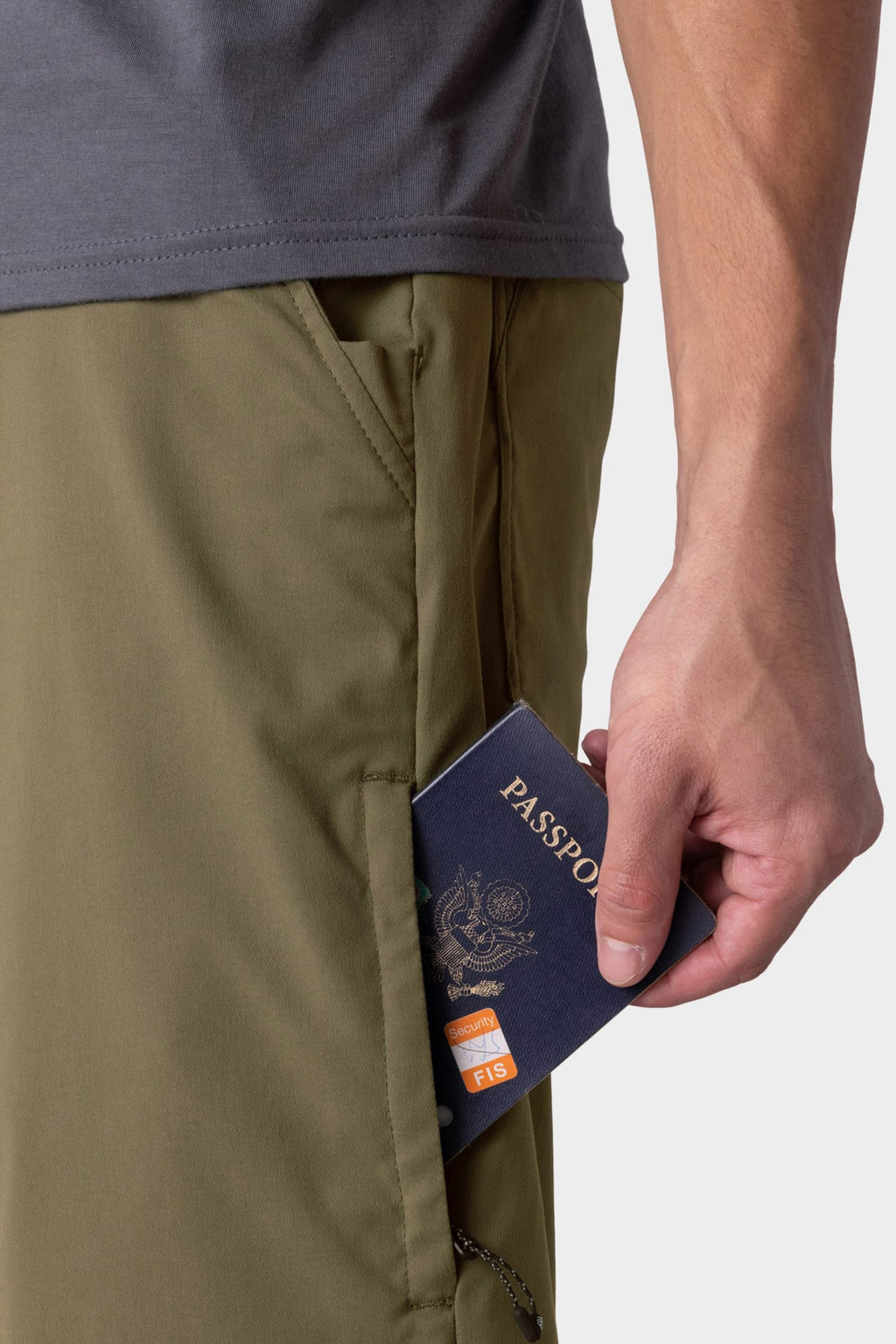A person in 686 Everywhere® Hybrid Short in olive green and a gray shirt puts a passport and orange card into the zippered side pocket of their breathable 686 shorts.