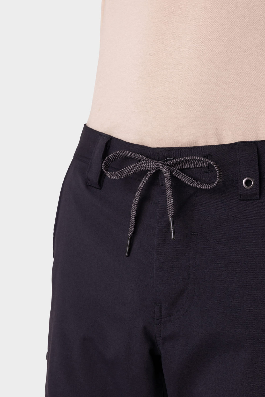 A man wears the 686 Men's Anything Cargo Pant – Slim Fit, featuring a bow-tied drawstring waist, paired with a beige shirt against a plain light background—ready for adventure.