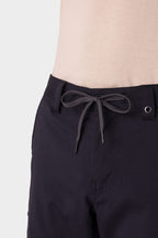 A man wears the 686 Men's Anything Cargo Pant – Slim Fit, featuring a bow-tied drawstring waist, paired with a beige shirt against a plain light background—ready for adventure.