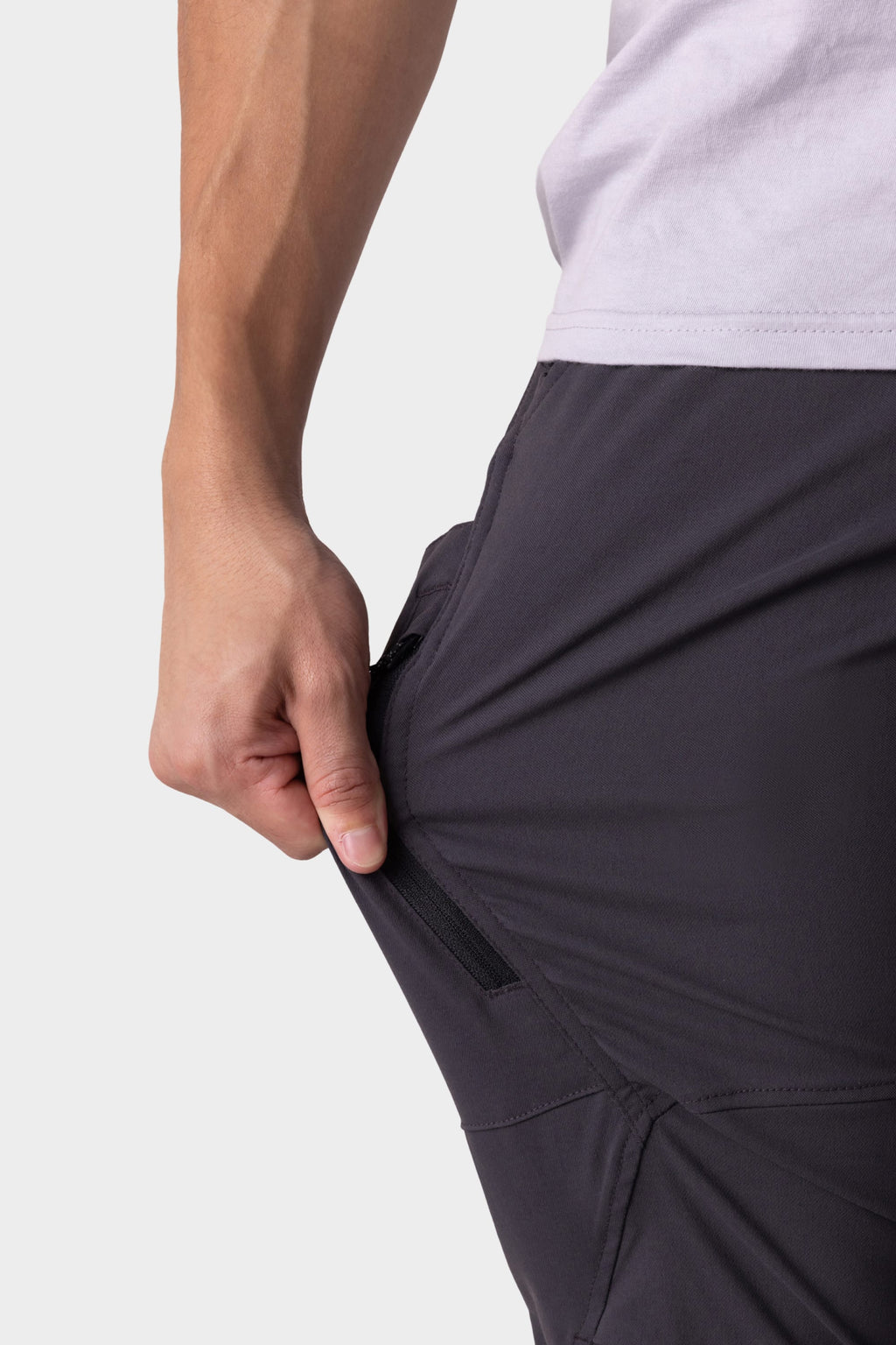 A person in 686 Men's Anything Cargo Pant - Slim Fit stretches the fabric sideways, highlighting its flexibility, zipper pocket feature, and adventure-ready design.