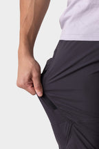 A person in 686 Men's Anything Cargo Pant - Slim Fit stretches the fabric sideways, highlighting its flexibility, zipper pocket feature, and adventure-ready design.