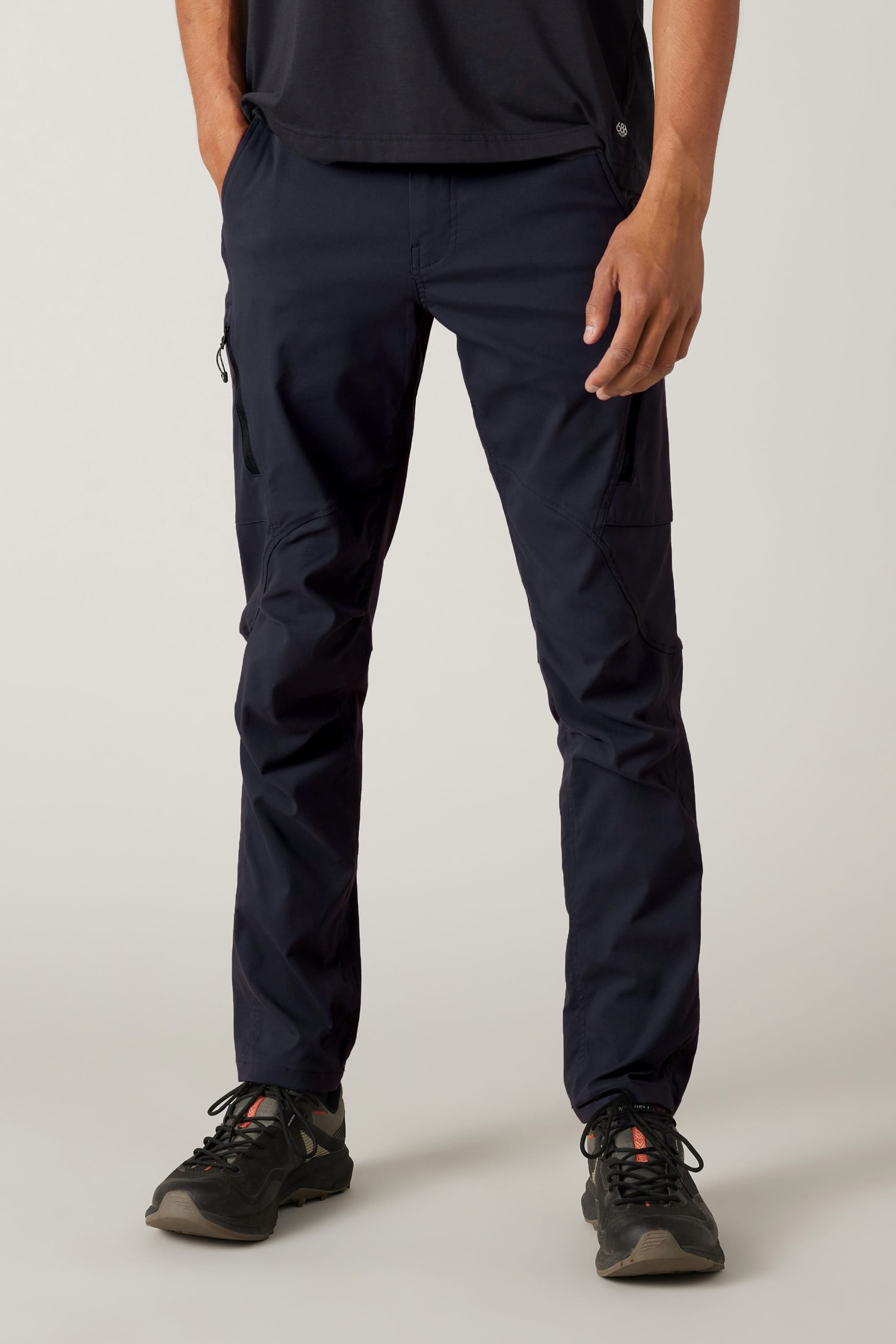 A person wearing black athletic shoes, a black shirt, and 686 Men's Anything Cargo Pant - Slim Fit by 686 with a 13-pocket design stands against a light background; only their lower half is visible—ready for any adventure.